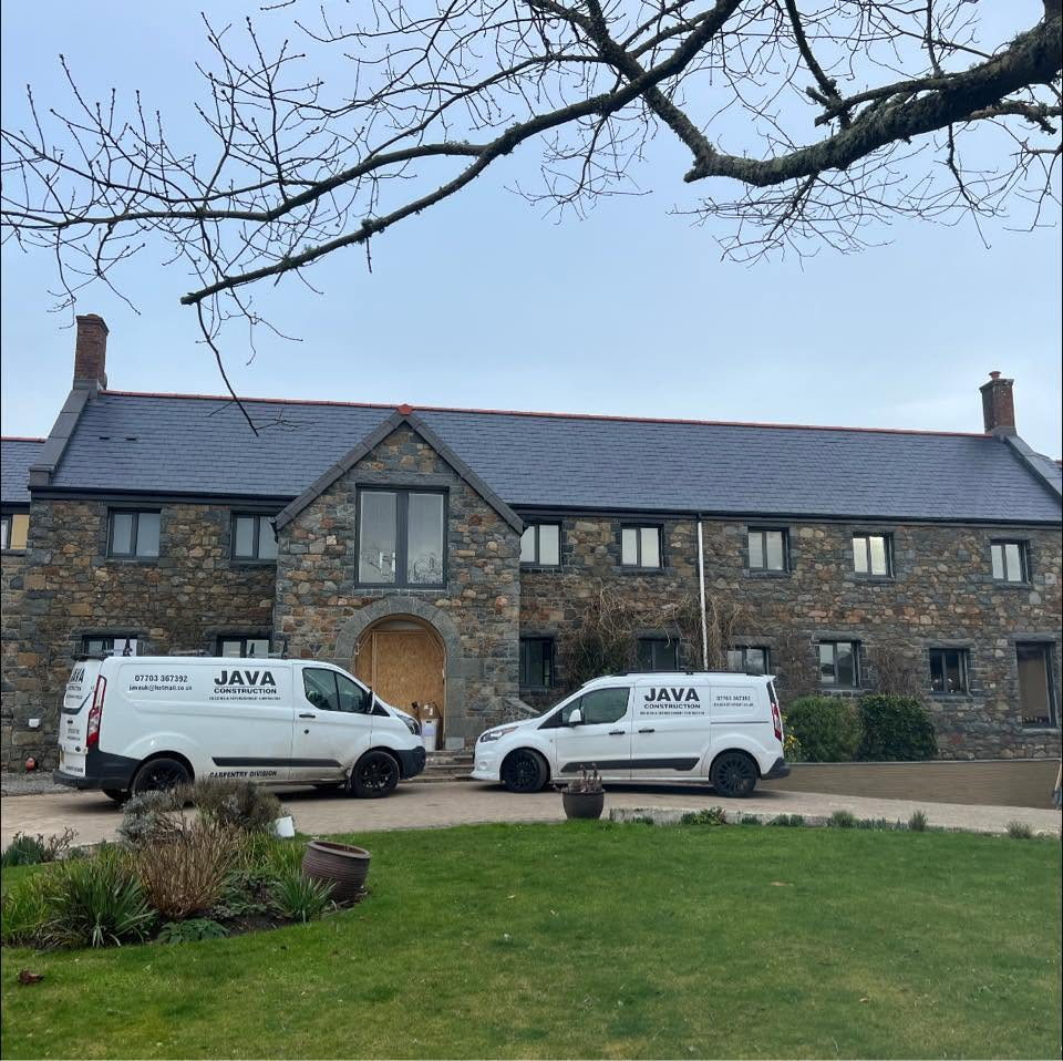Java Construction vans outside a completed Guernsey stone home